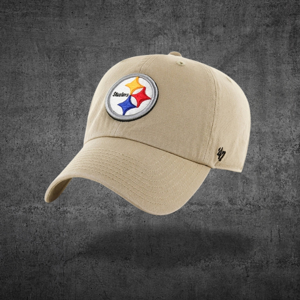 A tan baseball cap featuring the Pittsburgh Steelers logo on the front, displayed against a textured dark gray background.